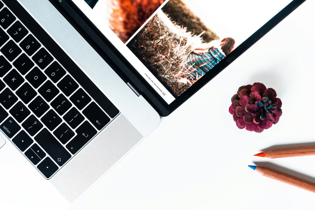 Laptop showing a photography website next to colored pencils, ready for website revisions and edits