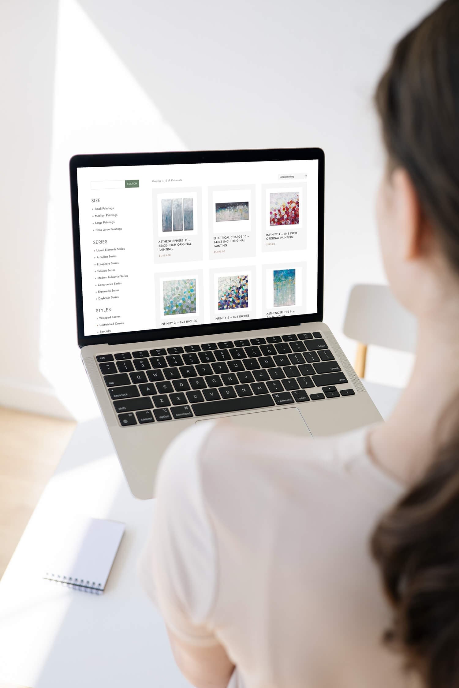 Woman holding a laptop showing a website