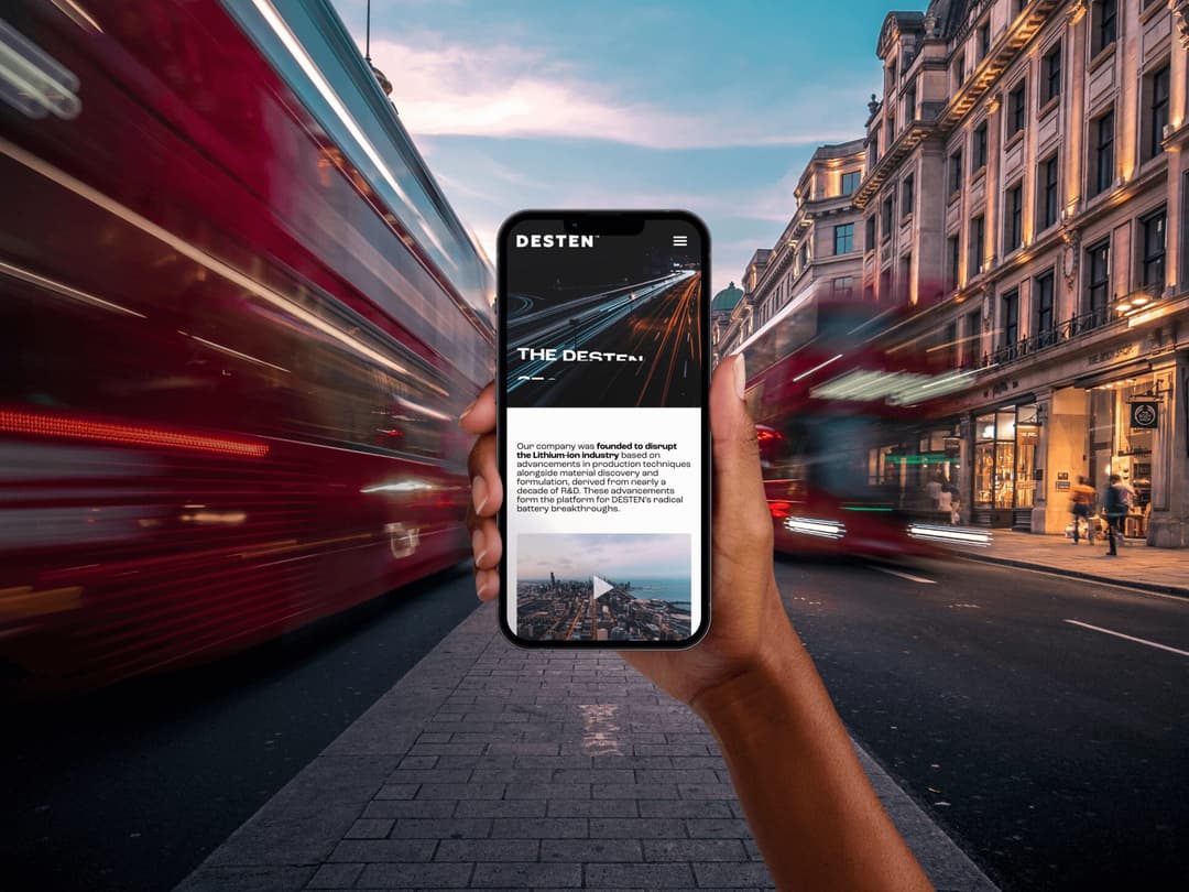 Person holding a phone showing a website on a busy street