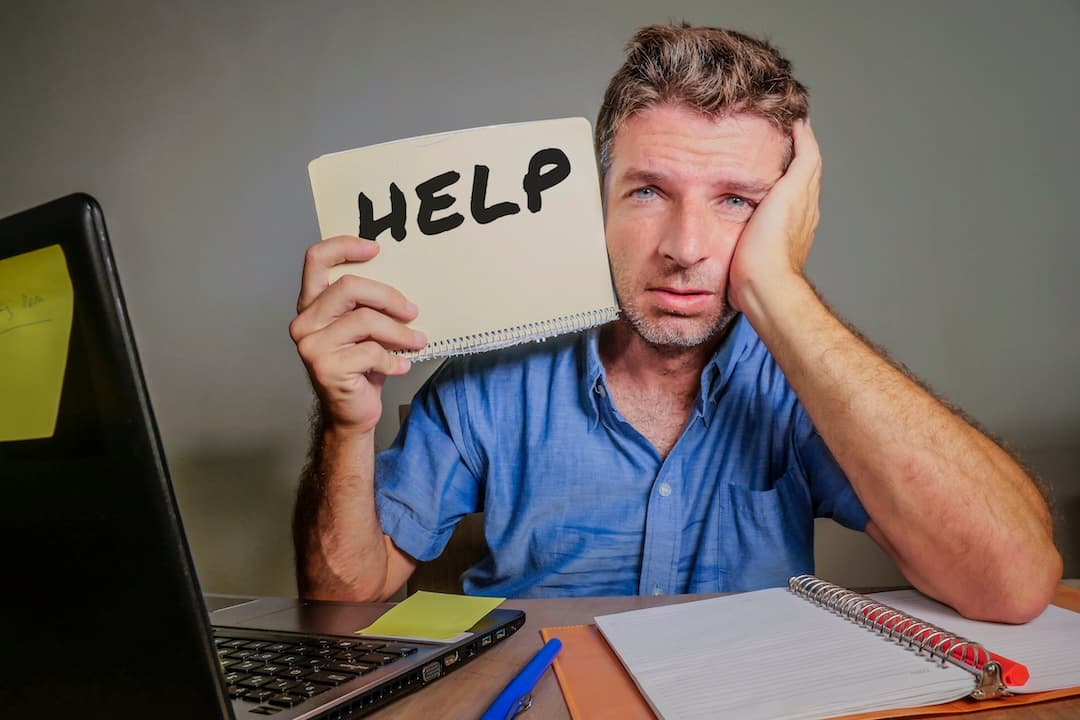 young desperate and stressed businessman feeling overwhelmed working with laptop computer at office desk sad suffering stress asking for help