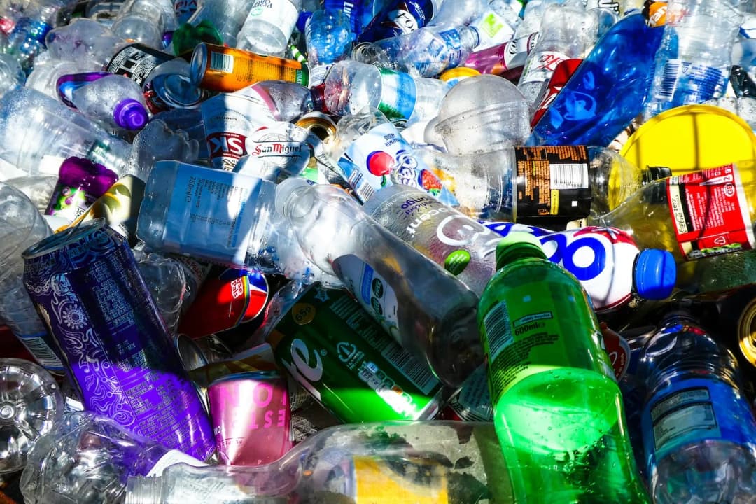Pile of plastic bottles, aluminum cans, and recyclable materials ready for sorting and recycling.