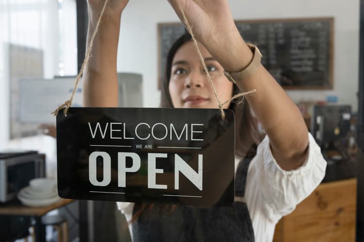 Small business owner turning an open sign, symbolizing website launch readiness and startup investment